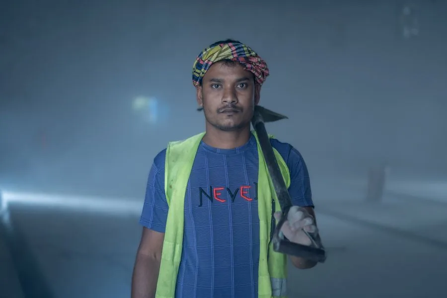 A construction worker in a safety vest and headscarf holding a spade