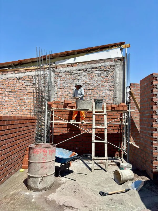 A bricklayer laying bricks on scaffolding
