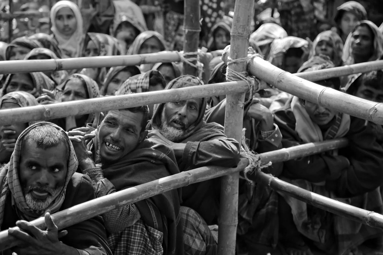 Workers waiting behind a bamboo barrier to be picked for the day